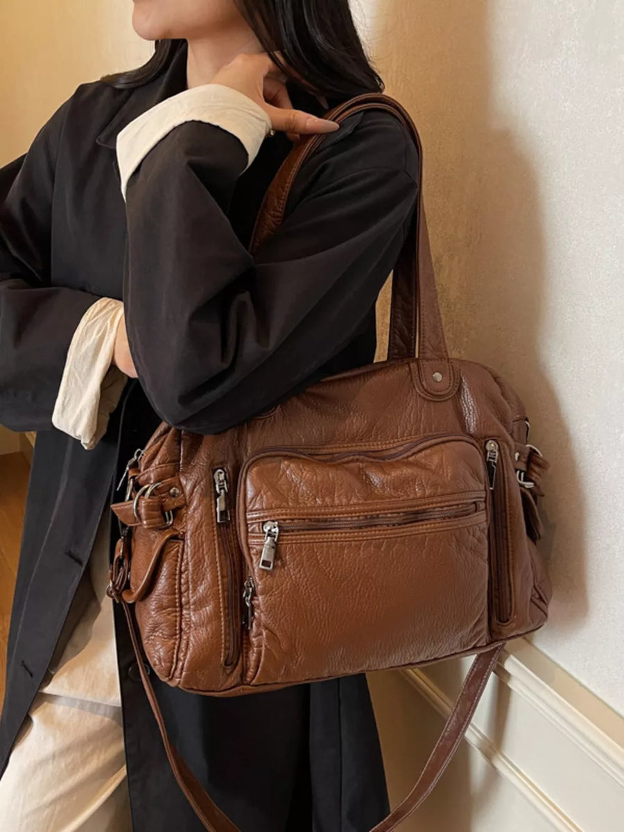 Brown faux leather crossbody bag with multiple zippered pockets and adjustable strap.