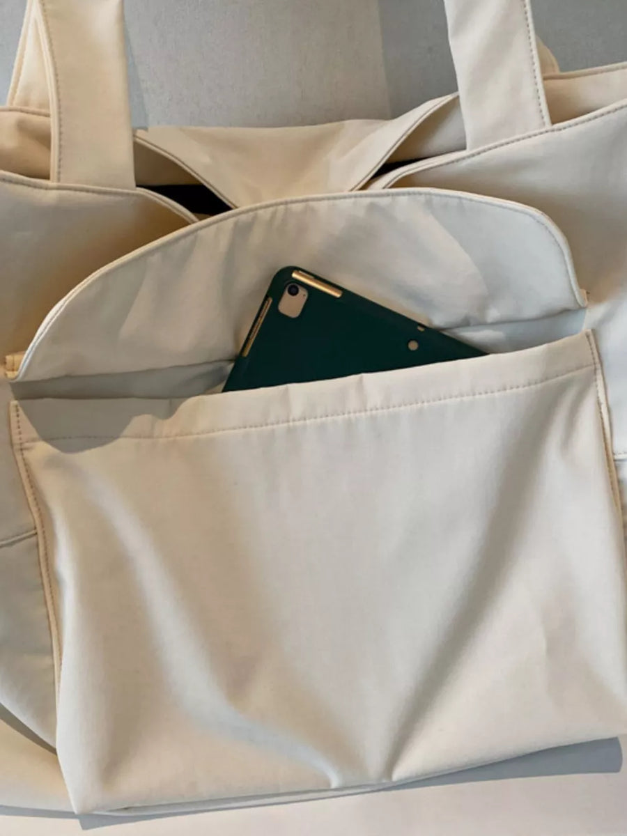 Spacious cream nylon shoulder bag with flap and exterior pocket holding a green tablet.