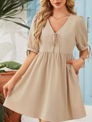 Apricot tied neck puff sleeve mini dress with pockets and tie detail on sleeves.