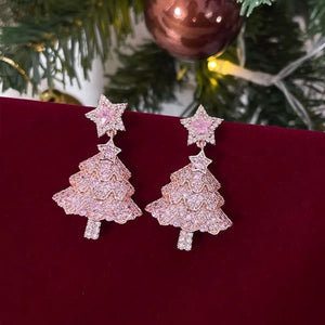 Blush pink Christmas tree dangle earrings with star accents, adorned with delicate shimmering stones.