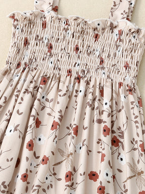 Baby jumpsuit with smocked bodice, floral print, and dragonfly accents.