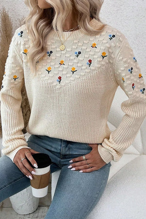 Beige embroidered round-neck sweater with dropped shoulders and a textured knit pattern.
