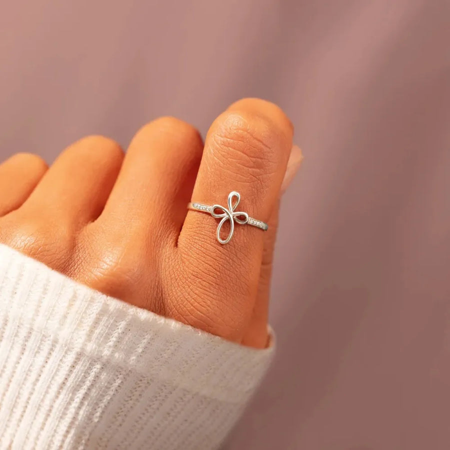 Delicate knotwork silver ring with crystals on a hand wearing a white sweater.