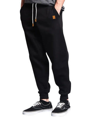 Black relaxed fit joggers with drawstring and leather detail.