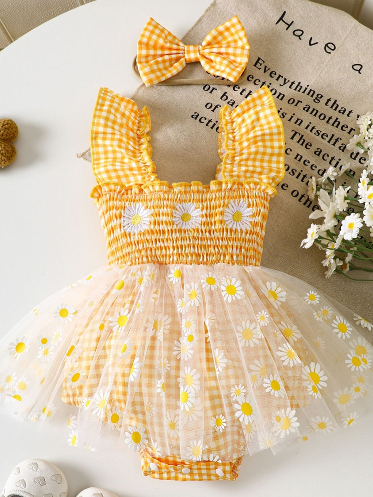 Yellow gingham baby one-piece with smocked bodice, daisy embroidery, and tulle skirt.