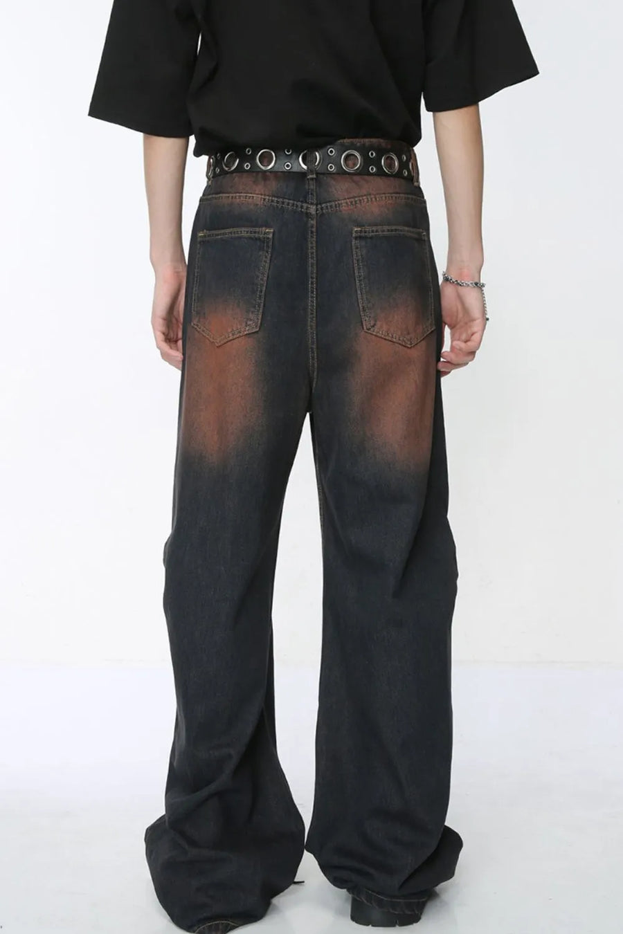 Acid wash flare jeans in dark denim with distressed detailing and stud belt.