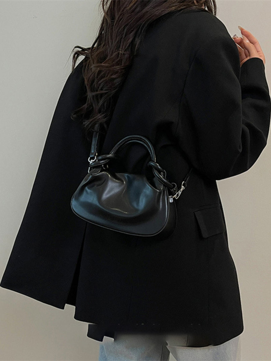 Black ruched crossbody bag with knot handle and adjustable strap.