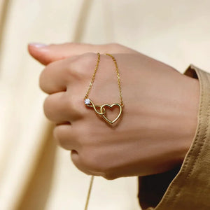Gold necklace with intertwined heart and infinity symbols, one clear stone accent.