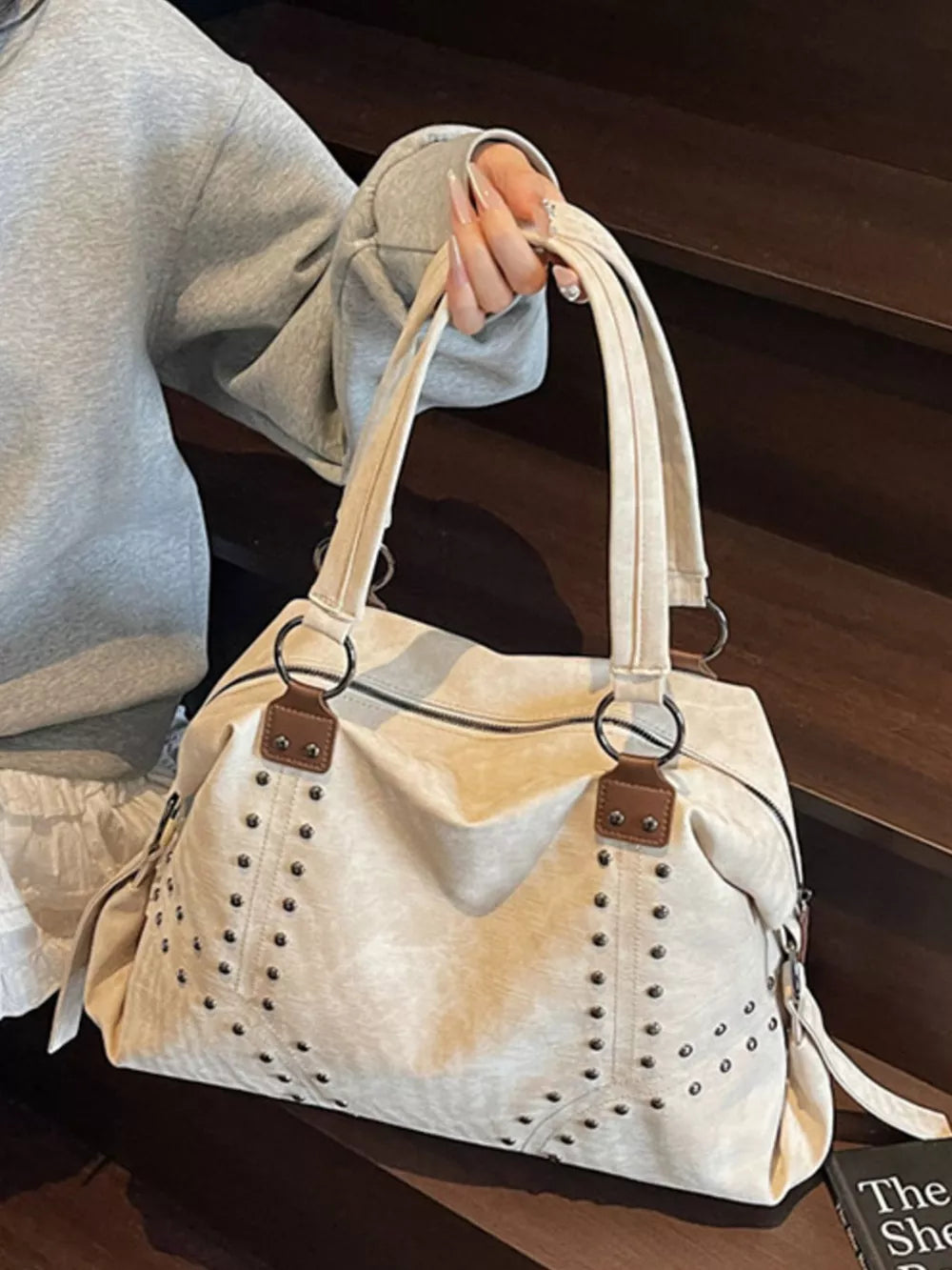 Cream white distressed studded trapezoid handbag with brown accents.