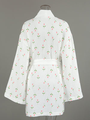 White cotton robe with pink floral print and green leaves, belted waist, kimono sleeves.