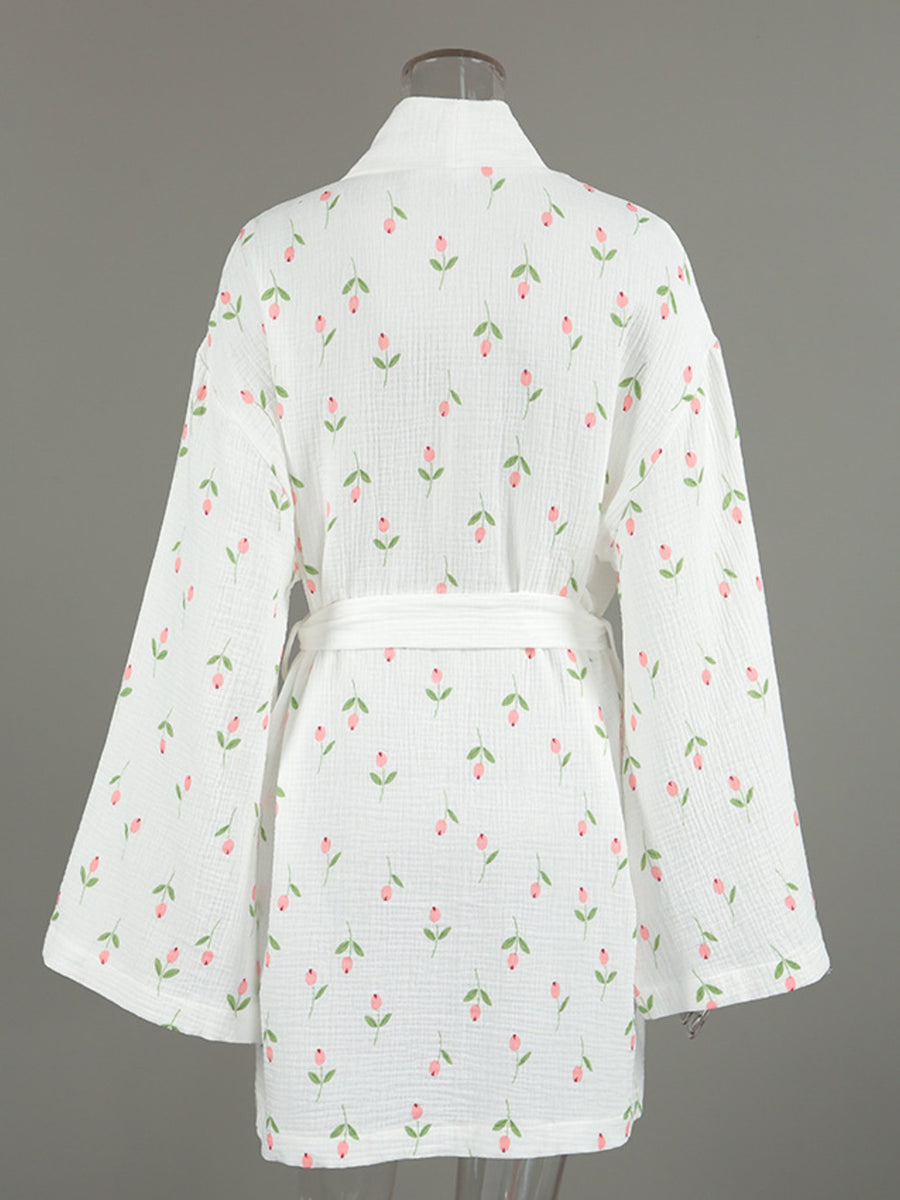 White cotton robe with pink floral print and green leaves, belted waist, kimono sleeves.