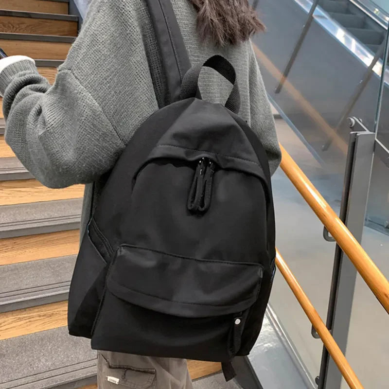 Black canvas school backpack with dual front pockets and zippers