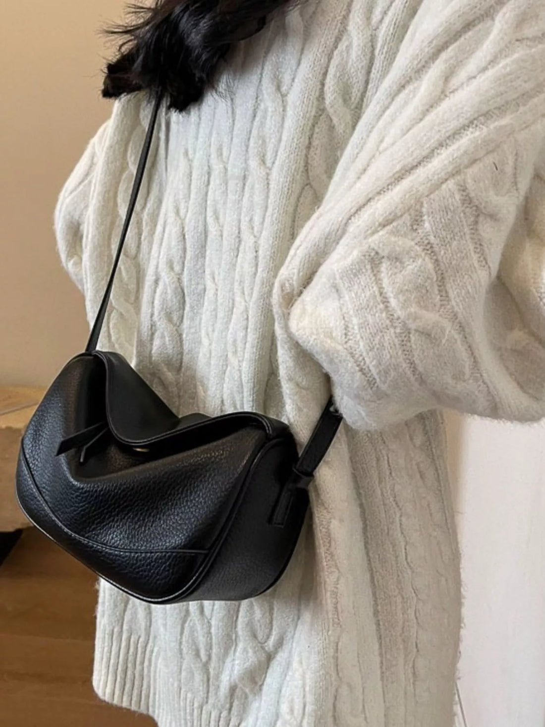 Black leather crossbody bag with textured finish and flap closure.