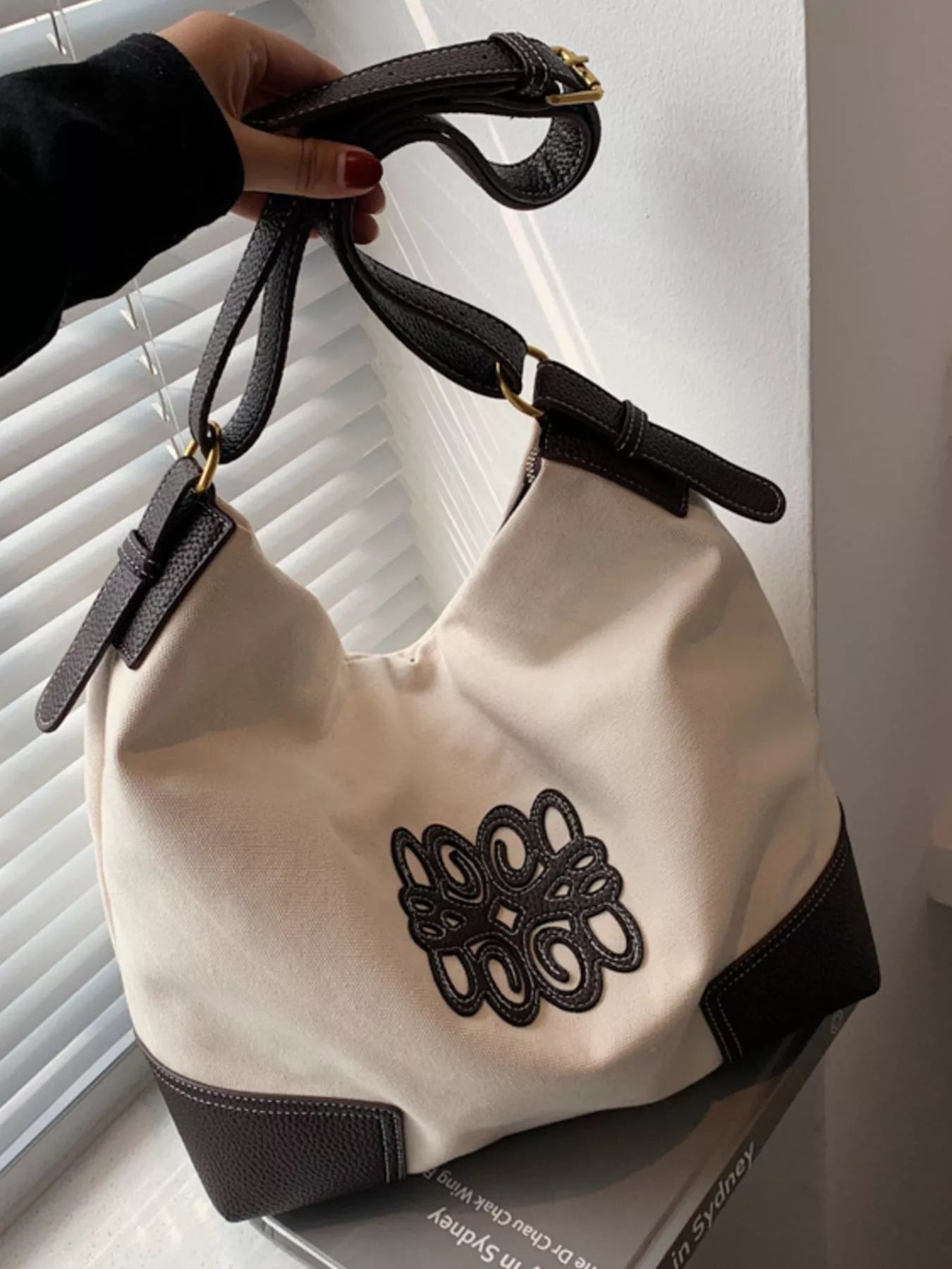 White canvas tote bag with dark brown trim and embroidered logo detail