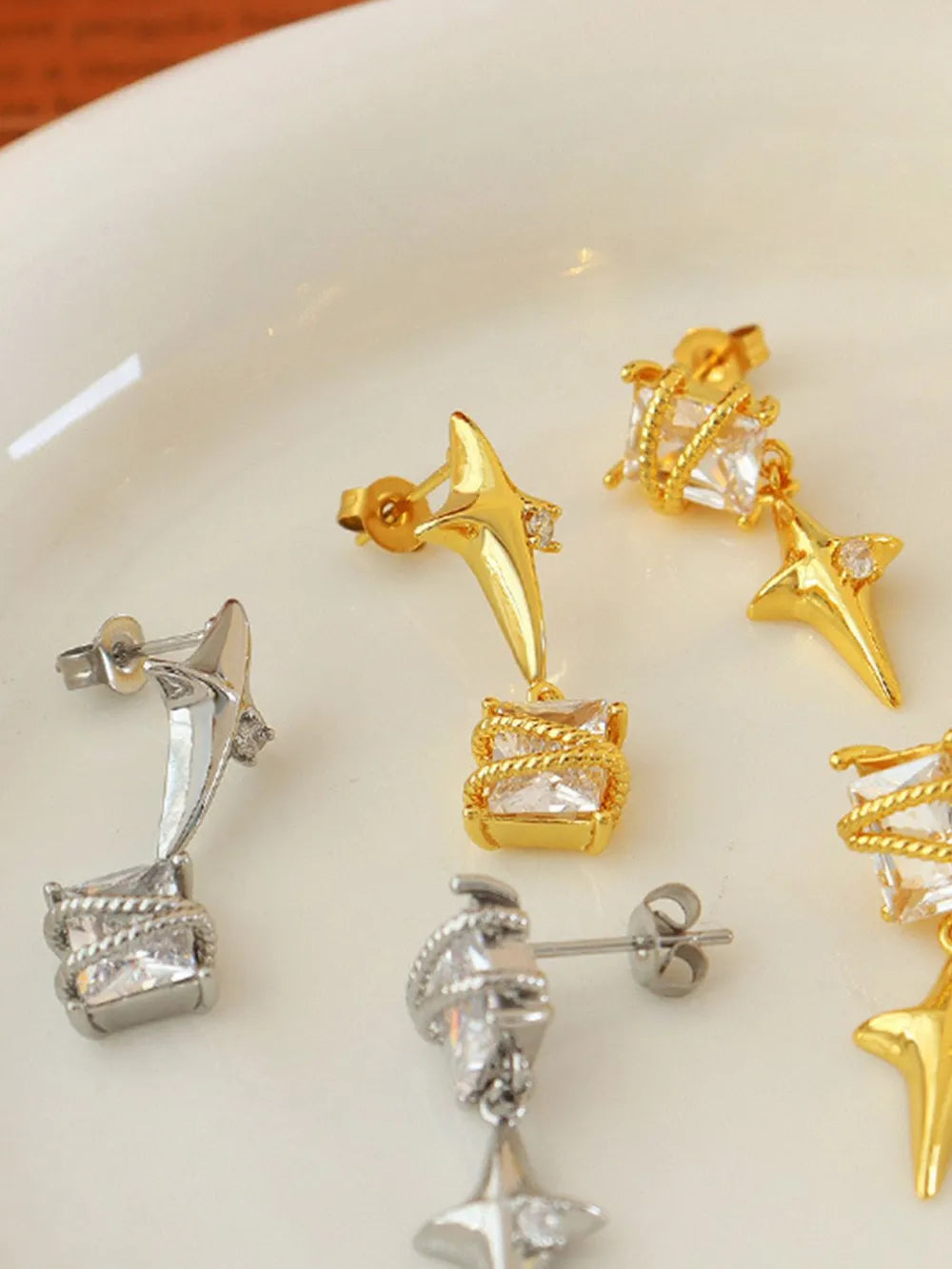 Silver and gold celestial starburst crystal drop earrings with square crystal accents.