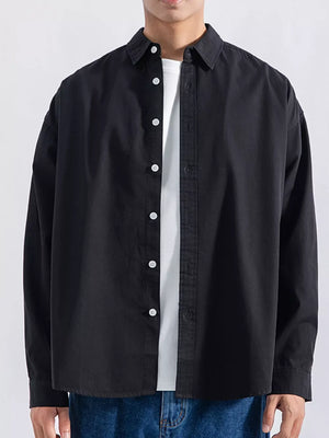 Men's black long sleeve button-up shirt with white buttons, worn over a white tee.