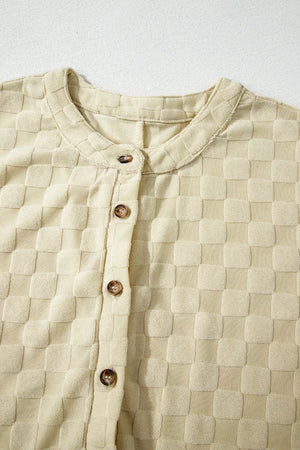 Textured sleeveless wide-leg romper in cream with a checkered pattern and band collar.
