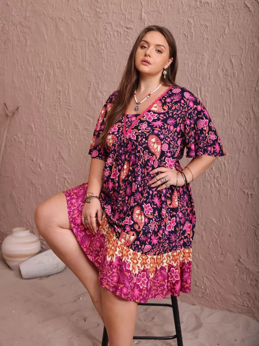 Plus-size floral flutter dress with ruched waist and tiered hem in navy, pink, and orange.