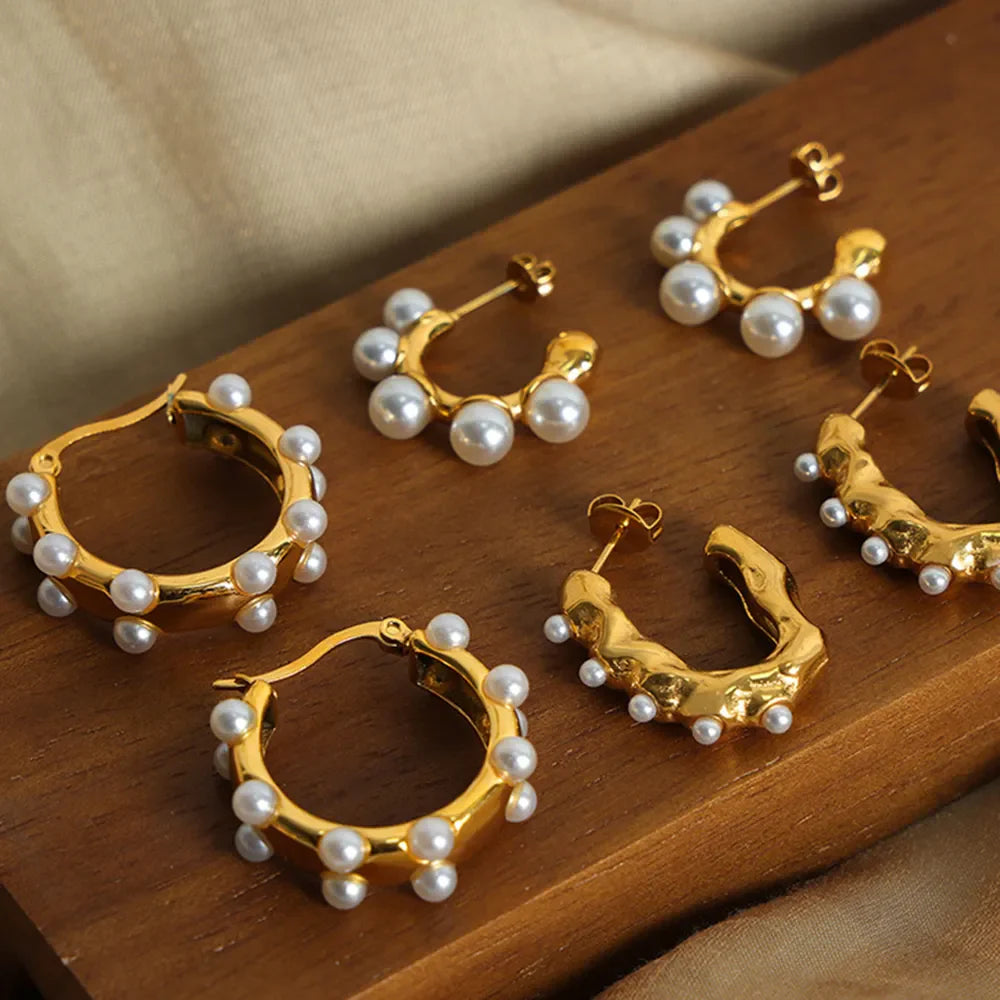 Gold hoop earrings with scattered pearls and sculpted details.