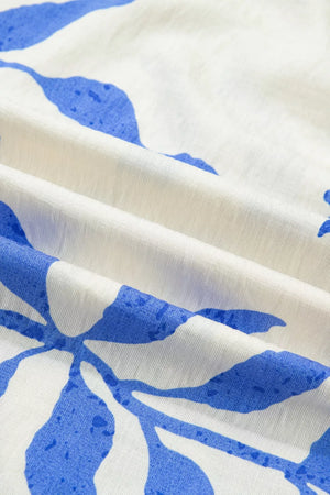 Maxi dress with blue botanical print on white fabric, showing texture and folds.