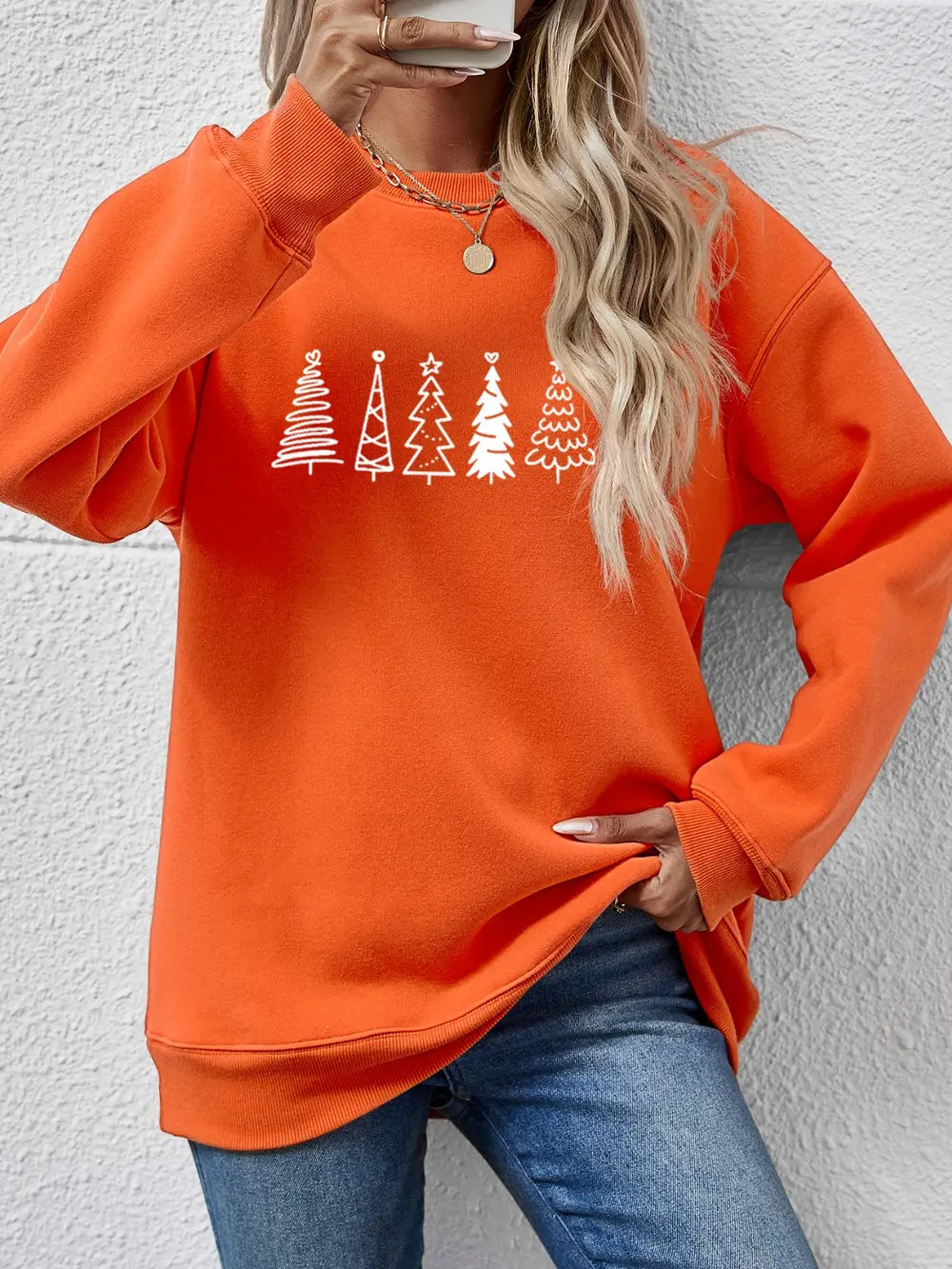 Orange oversized sweatshirt with white tree line graphic, crew neck, long sleeves.