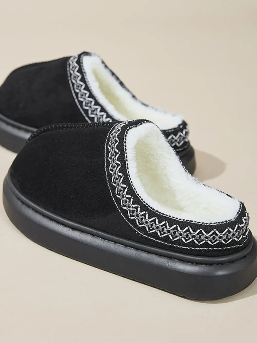 Black shearling house slippers with embroidered trim and thick sole