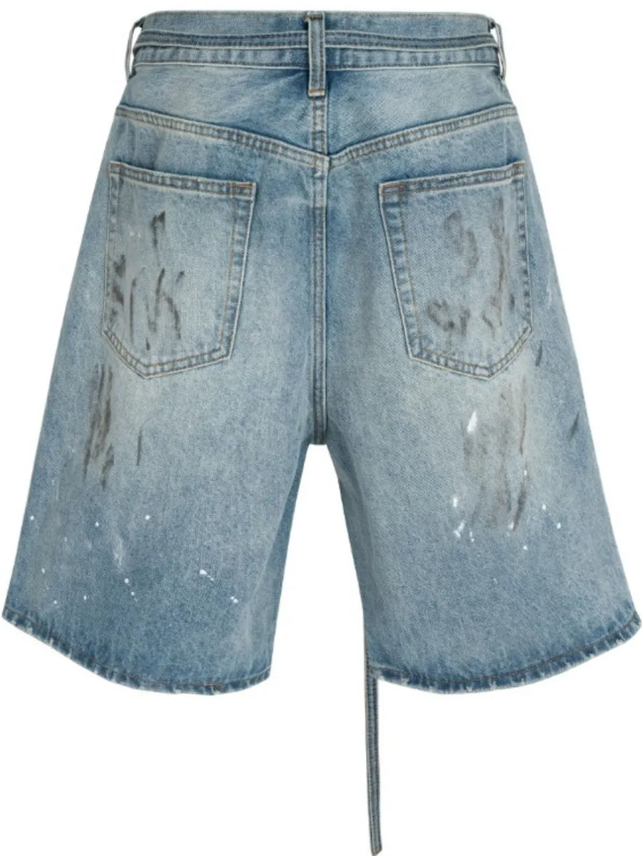 Distressed denim Bermuda shorts in medium wash with paint splatters and a tie detail.