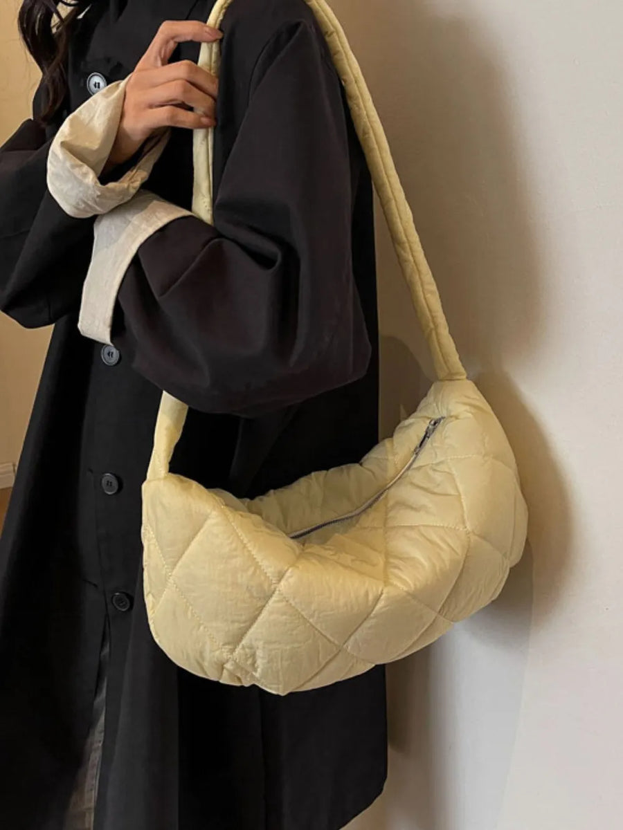 Quilted crossbody bag in pastel yellow with a zippered top and puffy strap.