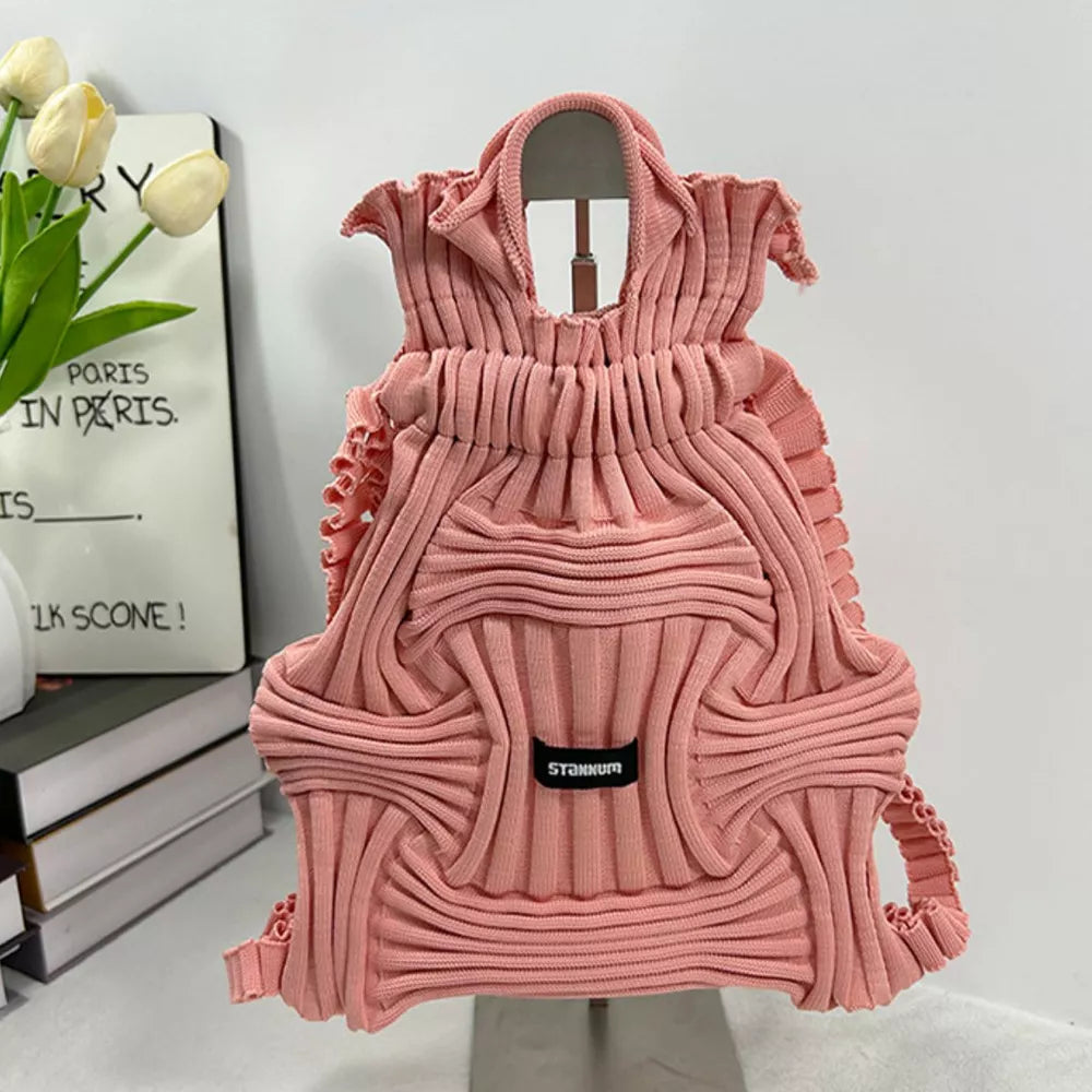 Pink textured knit medium backpack bag with ruching details and a black logo patch.