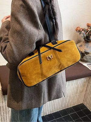 Yellow suede shoulder bag with gold clasp and black trim.