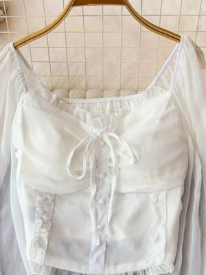 White maternity blouse with ruffled sleeves, square neckline, button front, and tie bow detail.