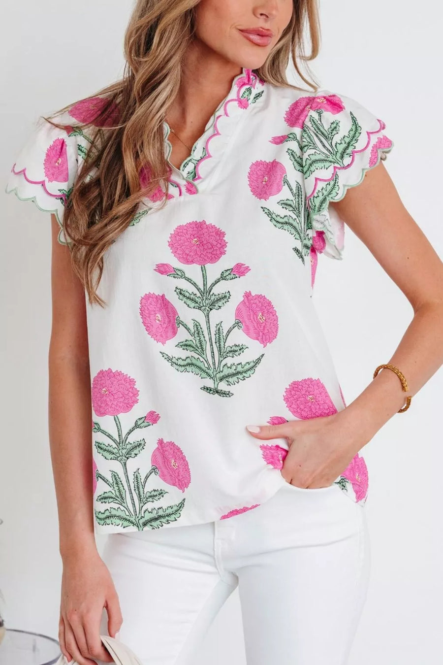 White cotton blouse with vibrant pink floral print, ruffled neckline, and scalloped sleeves.