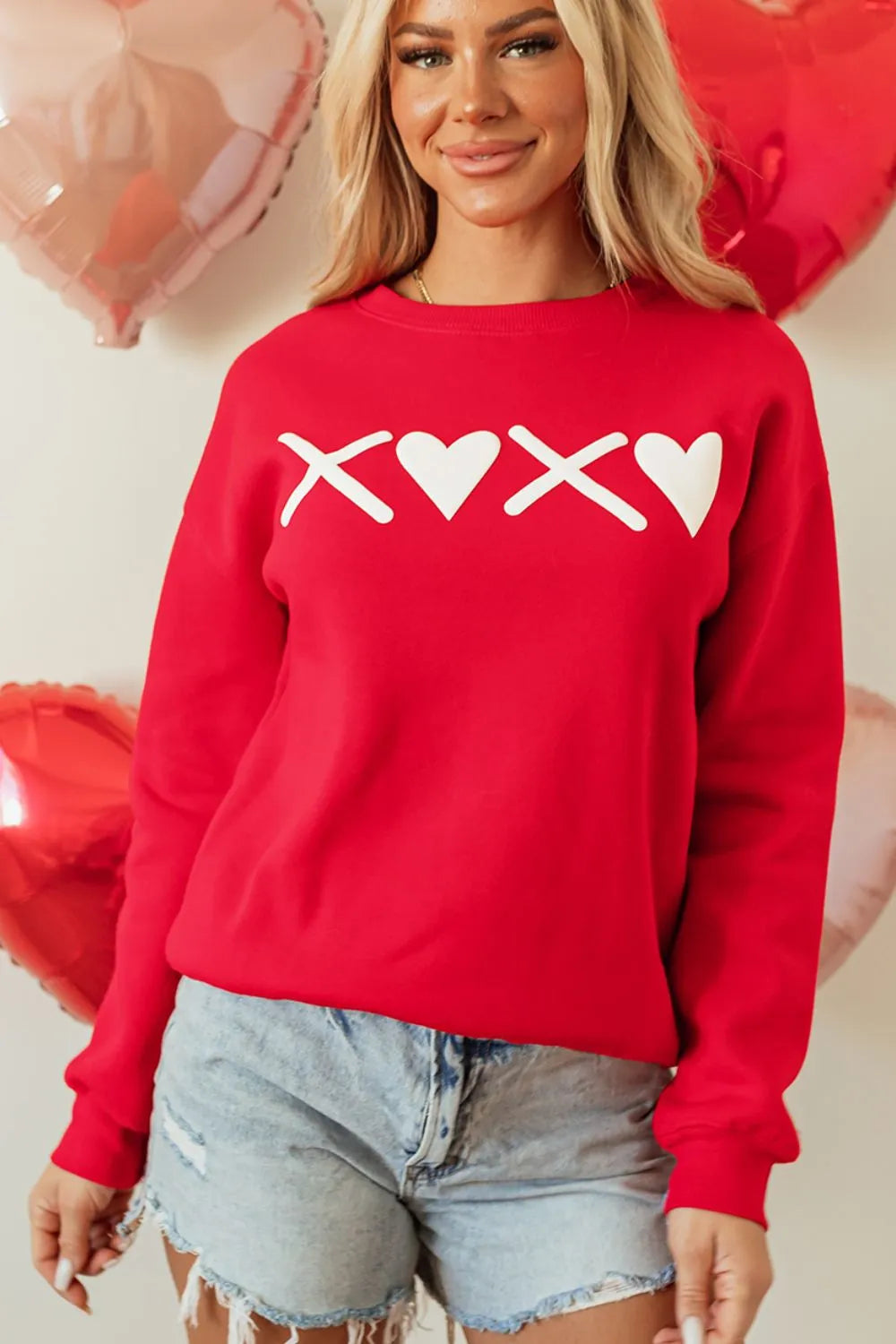Red crewneck sweatshirt with white XOXO graphic, crew neckline, and long sleeves.