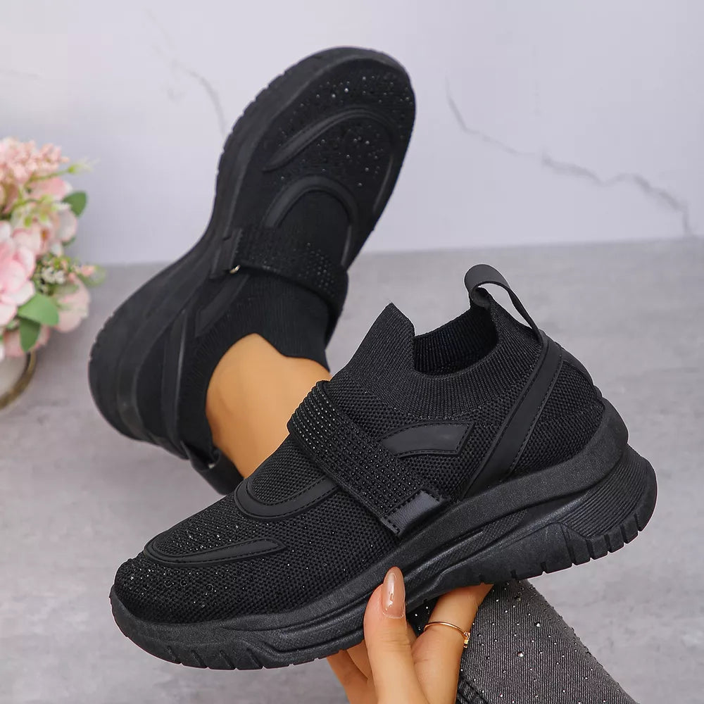 Black slip-on mesh sneakers with adjustable straps and rhinestone accents.