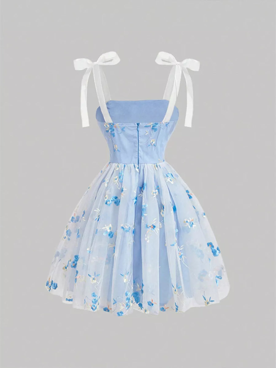 Blue floral embroidered mini dress with tie shoulder straps and a tulle overlay.
