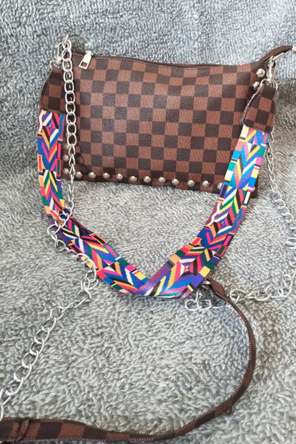 Brown checkered shoulder bag with studded detail and colorful geometric strap