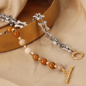 Silver asymmetrical bead and bone chain necklace with toggle closure.