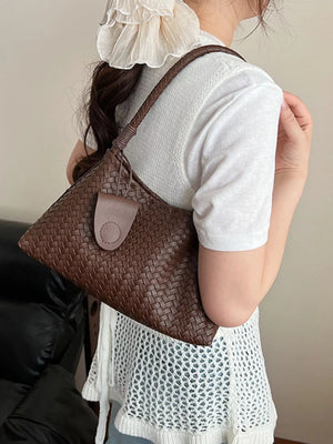 Woven shoulder bag in coffee color with a braided strap and flap closure.