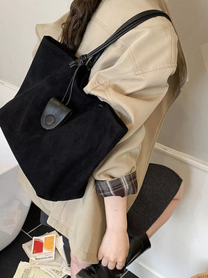 Large black suede tote bag with leather strap and button detail.