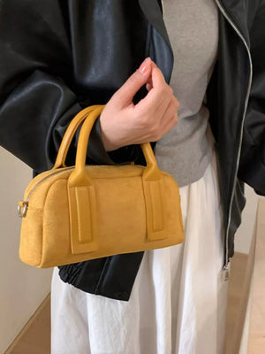 Chic yellow suede crossbody bag with top handles and zipper closure.