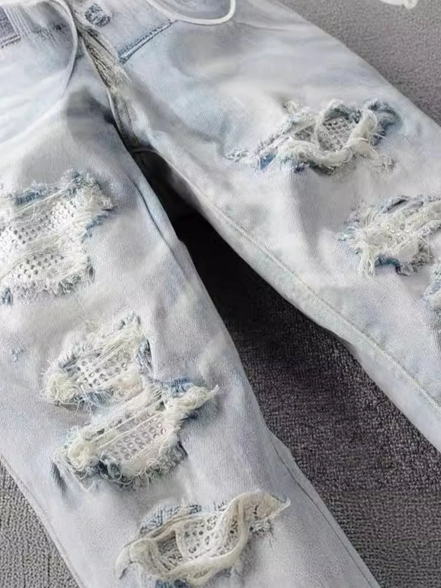 Light wash distressed slim-fit jeans with ripped details and white mesh underlay.