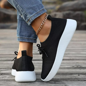Black lace-up sneakers with white mid sole and ribbed texture.