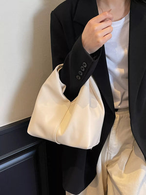 Knot handle medium leather shoulder bag in white, shown with a black blazer.
