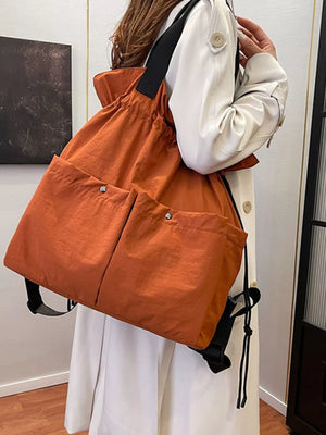 Orange drawstring backpack with two front snap pockets and black straps.