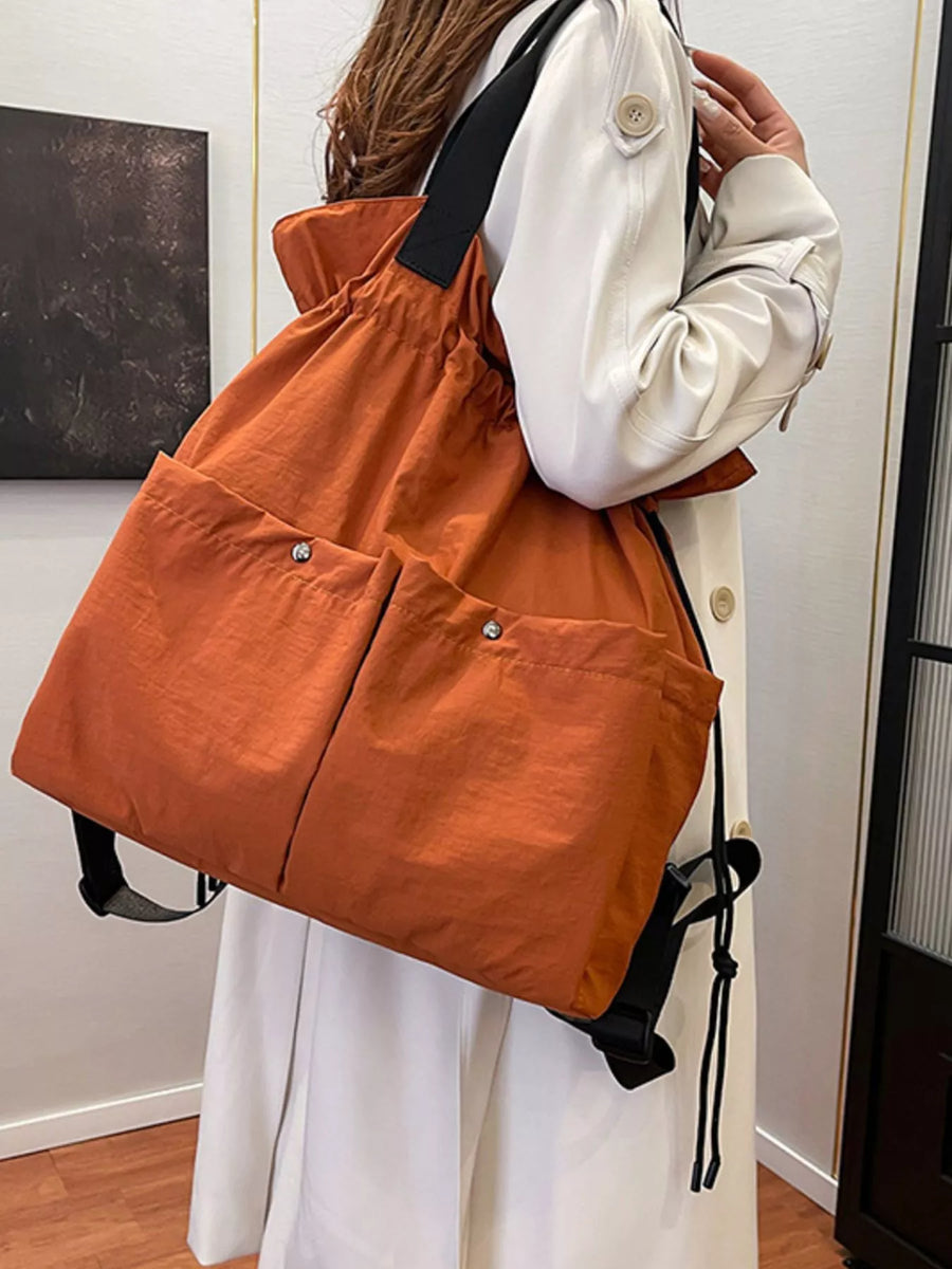 Orange drawstring backpack with two front snap pockets and black straps.