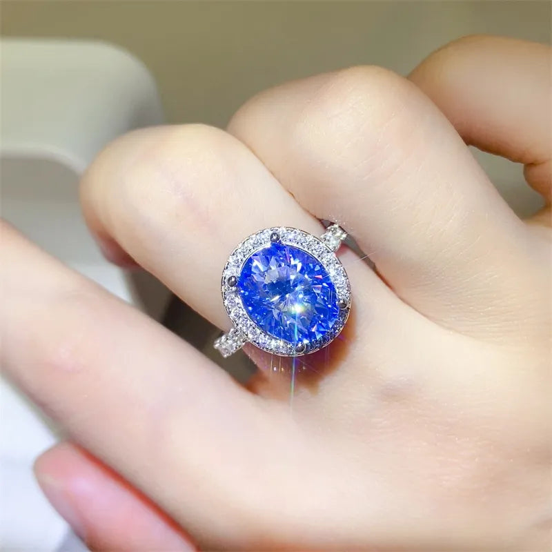 Silver halo ring with oval blue moissanite center stone and diamond accents.