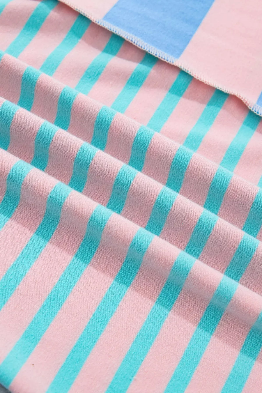 Striped knit fabric in pink and teal with a blue stripe detail.