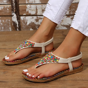 Beige thong sandals with colorful beadwork and elastic ankle strap.