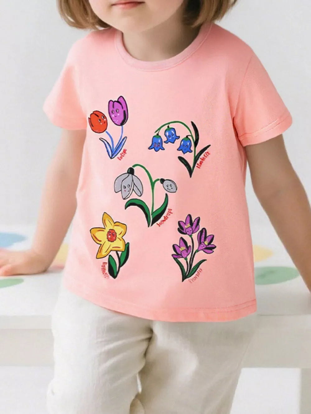 Toddler pink t-shirt with whimsical cartoon flower print, short sleeves, crew neck.