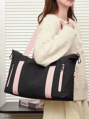 Black Oxford cloth travel bag with pink stripe accents and pink strap.